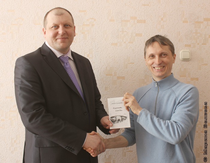 Михаил Придворов дарит Алексею Паташенко книгу для школьной библиотеки